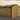 Wooden shed with a black roof in a rural setting during sunset.