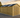 Wooden shed with a black roof in a rural setting during sunset.