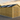 Wooden shed with a black roof in a rural setting during sunset.